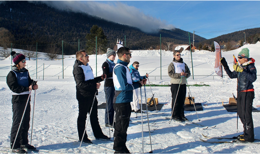 Un groupe de personnes se tient debout dans la neige en tenant des bâtons de ski.