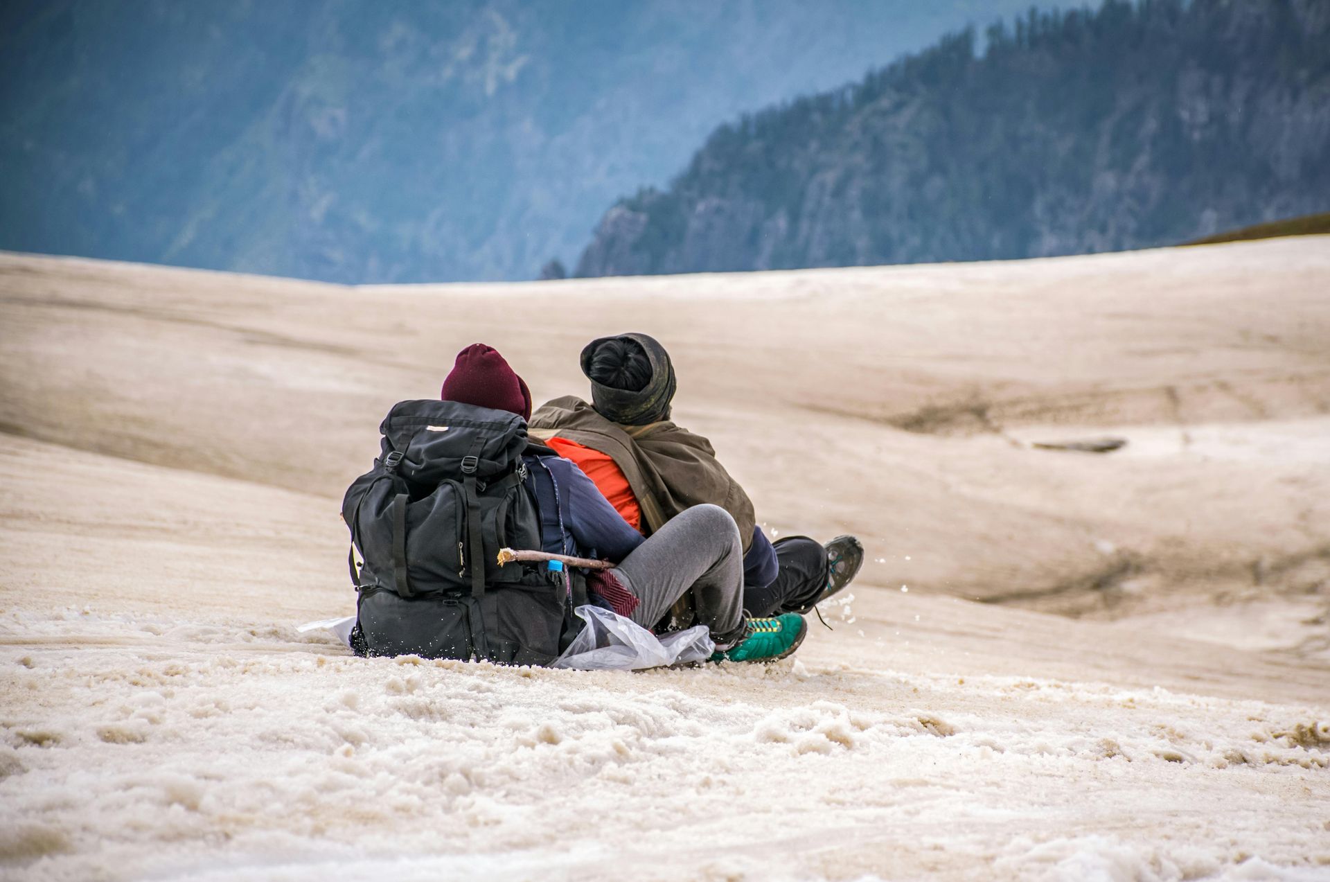 Deux personnes sont assises au sommet d'une colline couverte de neige.