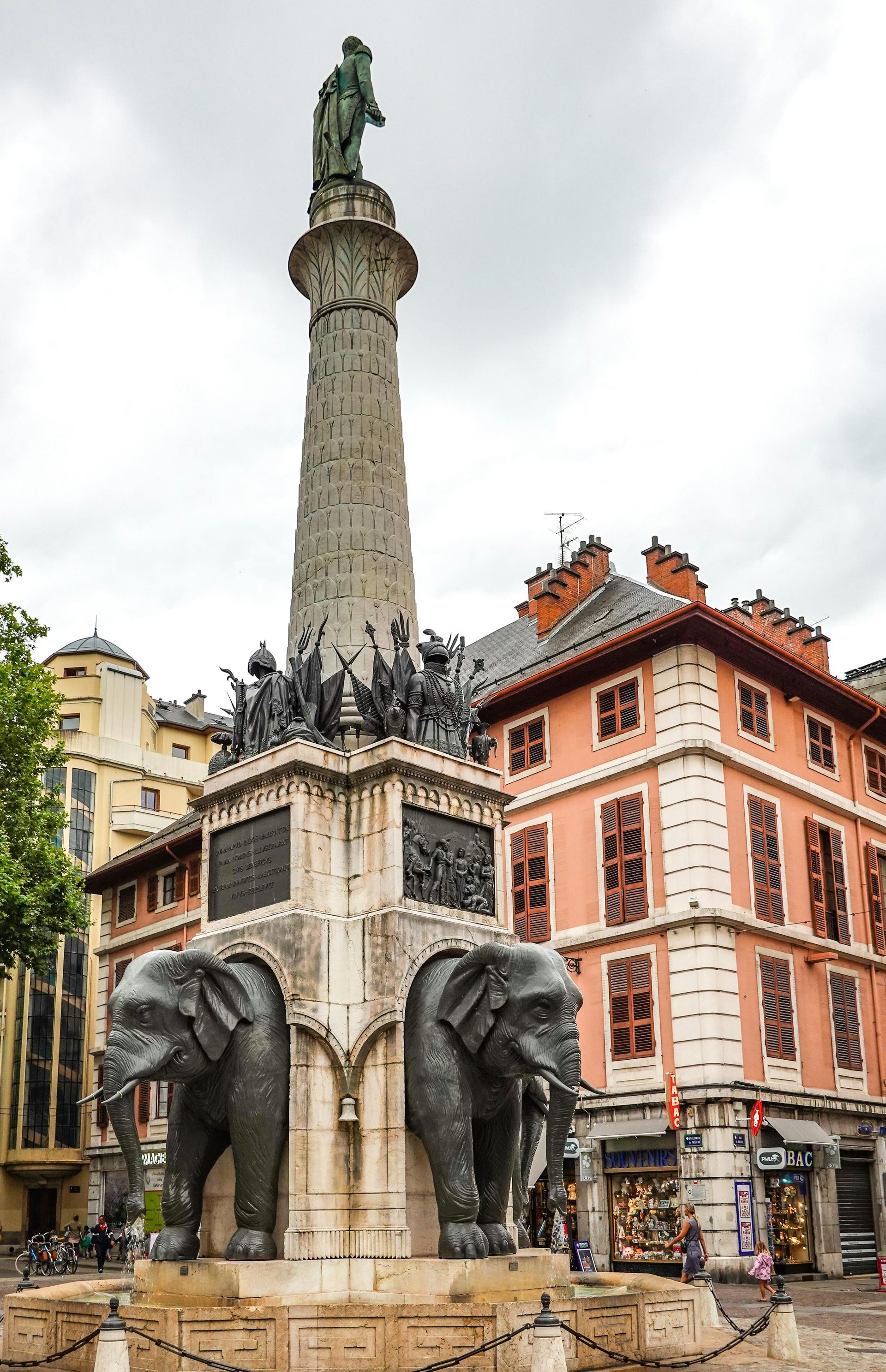 Une statue de deux éléphants debout l'un à côté de l'autre devant un bâtiment.