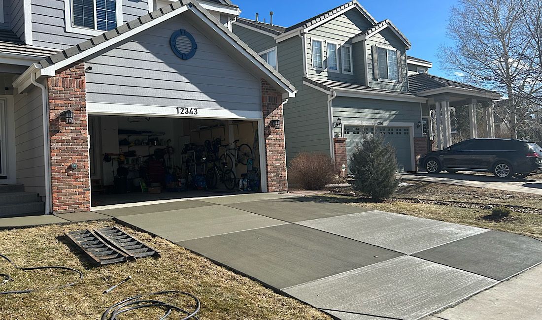 Suburban house with open garage, concrete driveway, and parked SUV under a clear blue sky