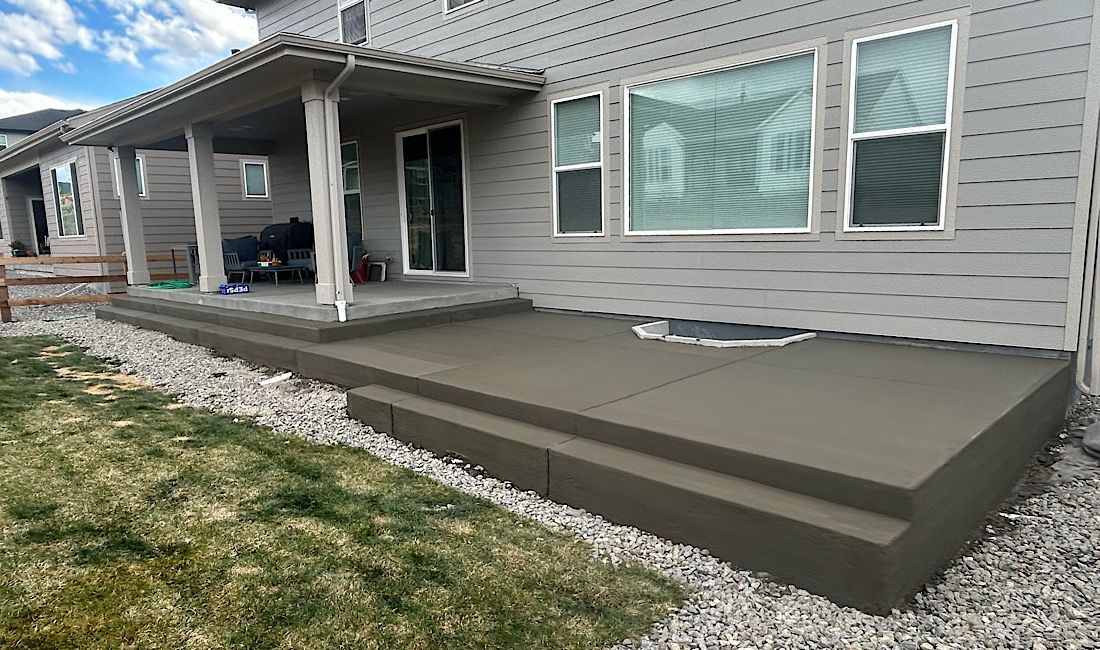 Back patio with gray siding, white trim, and a large dark gray concrete step platform.