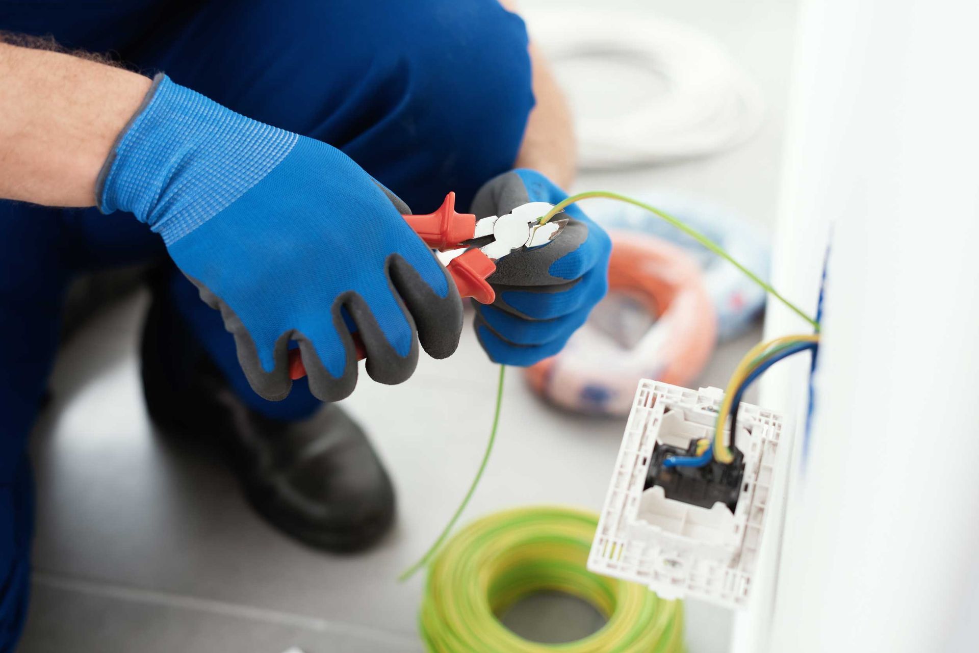 A skilled local electrician using insulated tools to repair a residential fuse box safely. A skilled local electrician using insulated tools to repair a residential fuse box safely.