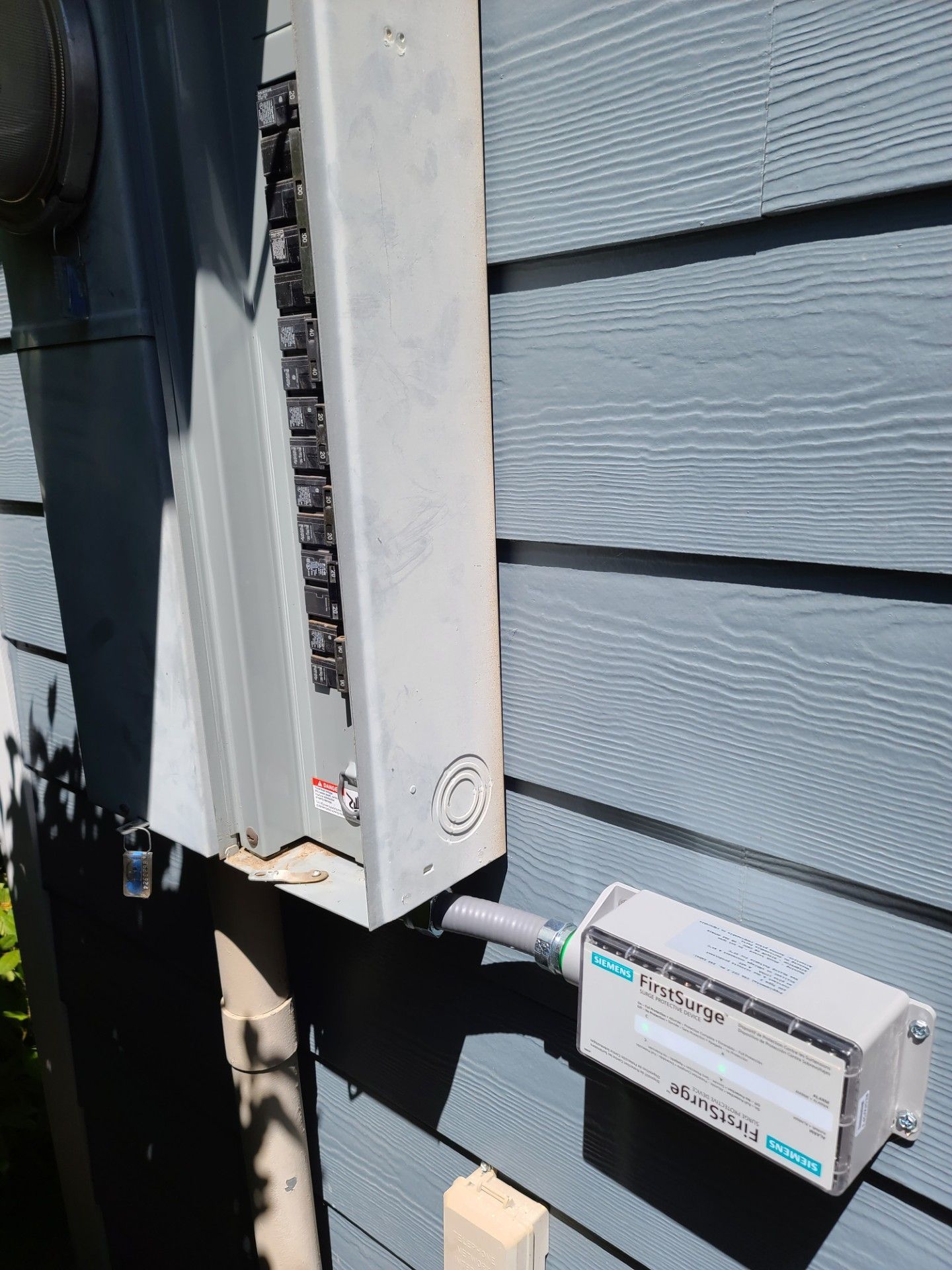 Outdoor electrical meter and conduit box mounted on a house wall with wiring visible