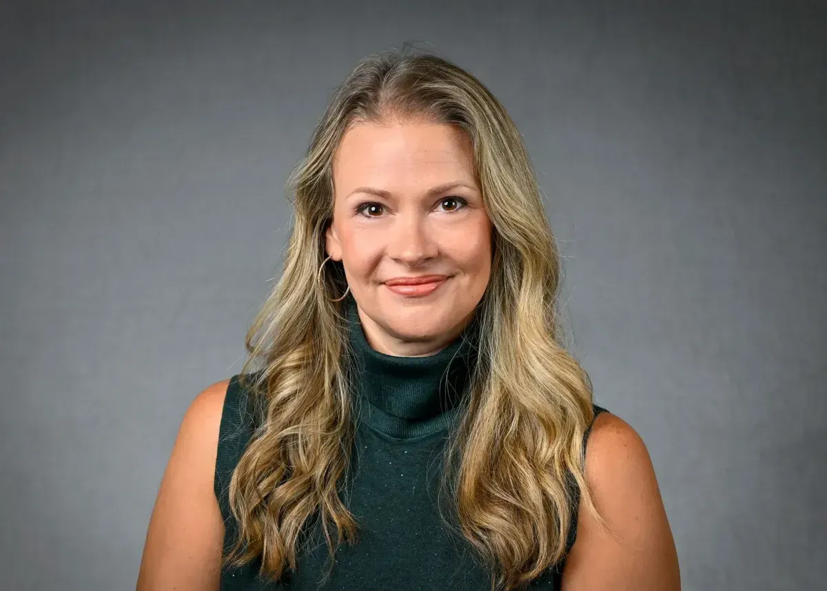 Professional woman in a black blazer smiling in a bright office setting