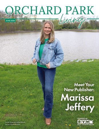 Marissa Jeffery stands by a pond on Orchard Park Living cover, wearing a denim jacket and jeans.