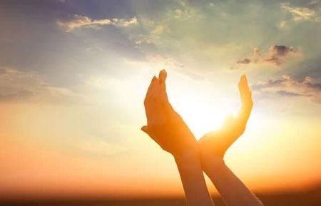 This is an image of hands appearing to hold up the sun.