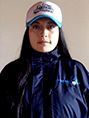 Una mujer que lleva un sombrero y una chaqueta mira a la cámara.