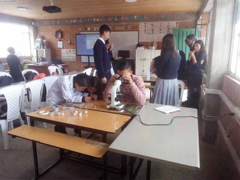 Un grupo de estudiantes está mirando a través de un microscopio en un aula.