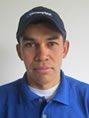 Un hombre que lleva una camisa azul y un sombrero mira a la cámara.