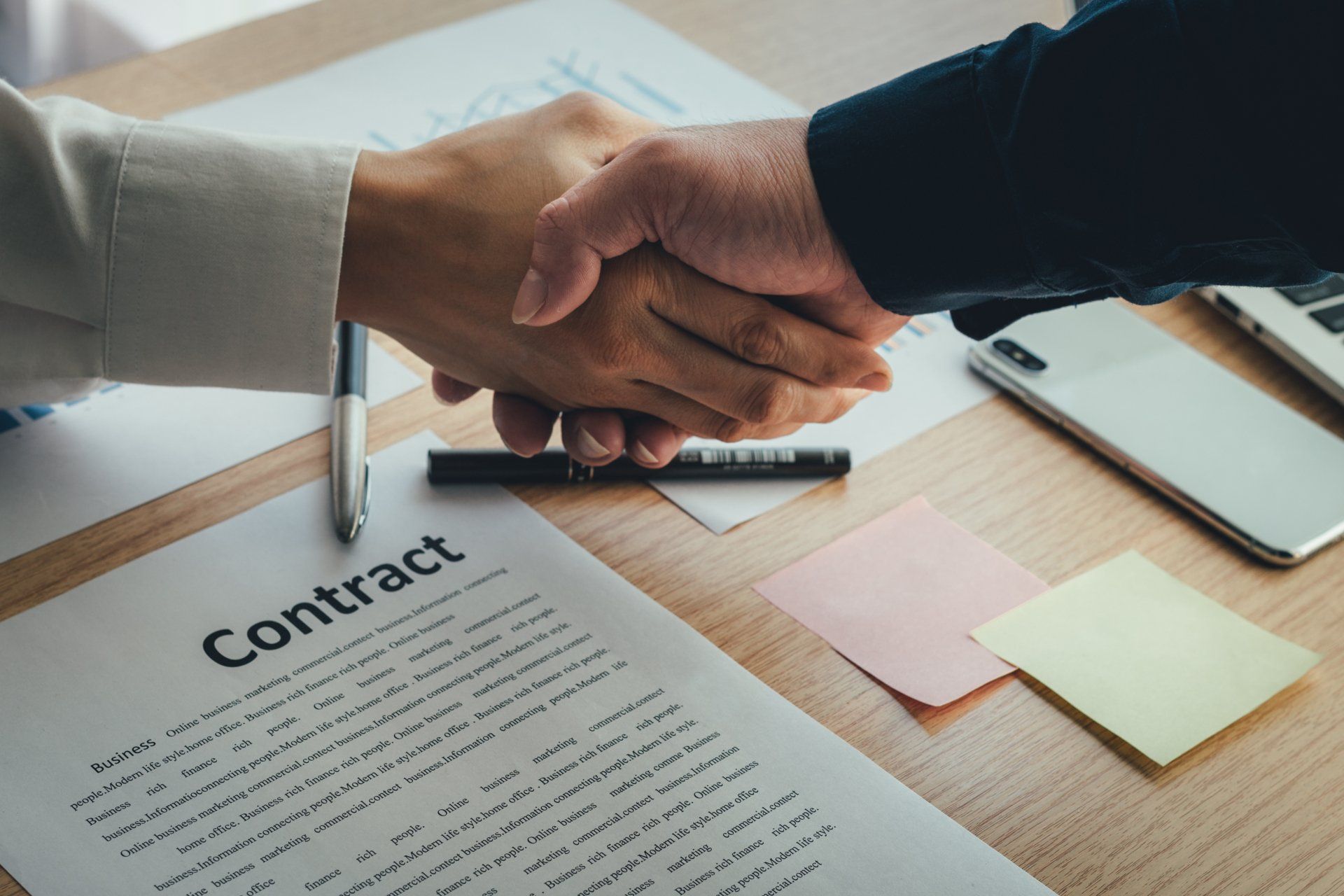 a man and a woman are shaking hands over a contract .