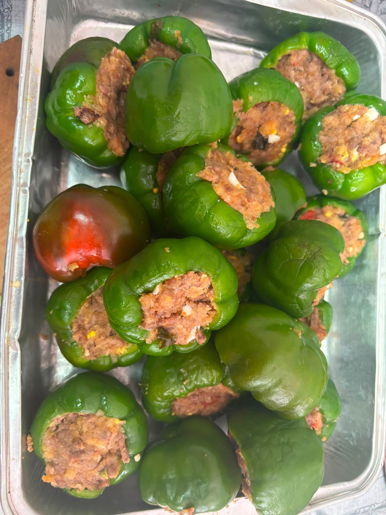 Vassoio di peperoni verdi ripieni, con un peperone rosso ripieno di un composto di carne macinata.