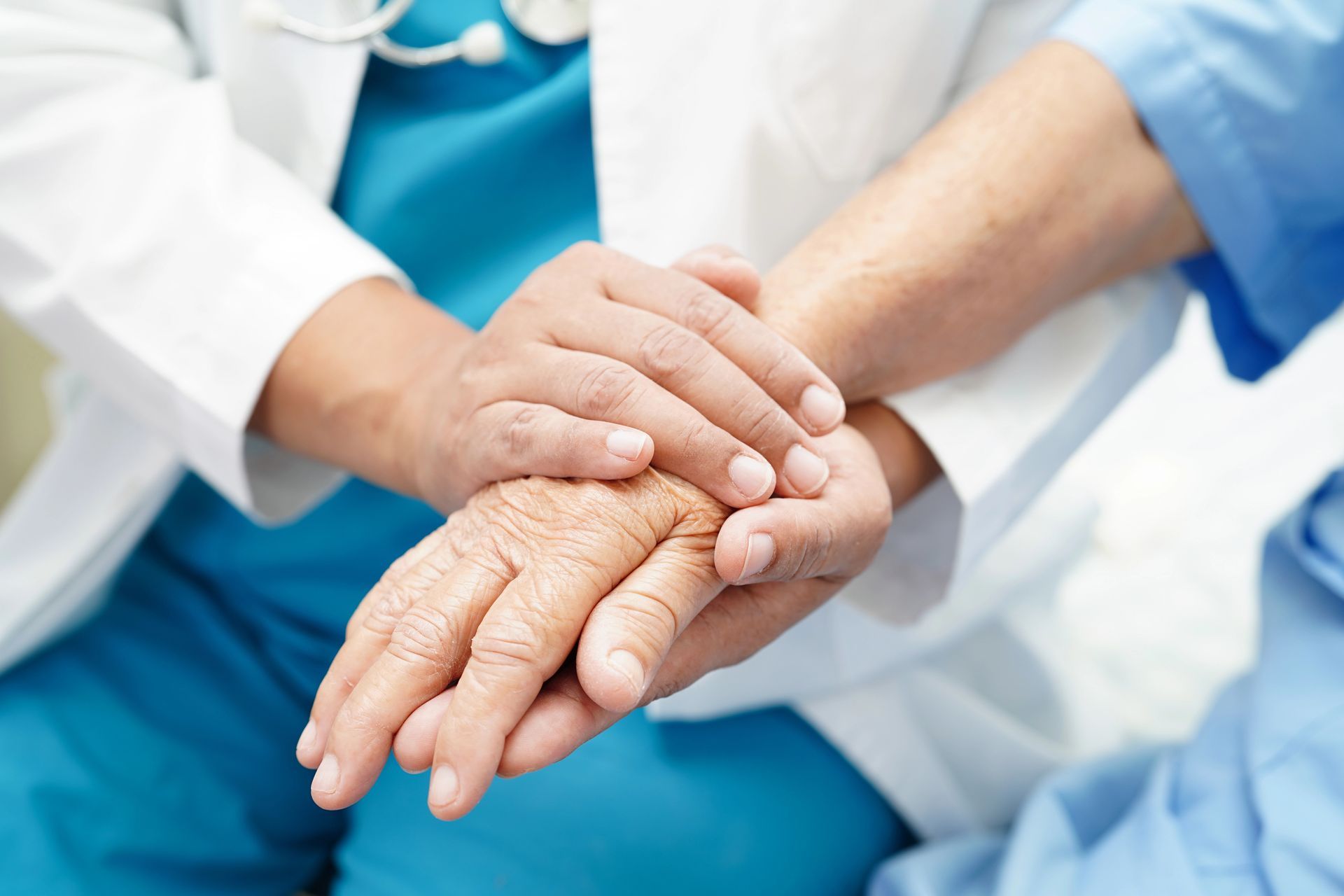 Un medico tiene delicatamente la mano di un paziente anziano in un ambiente ospedaliero.