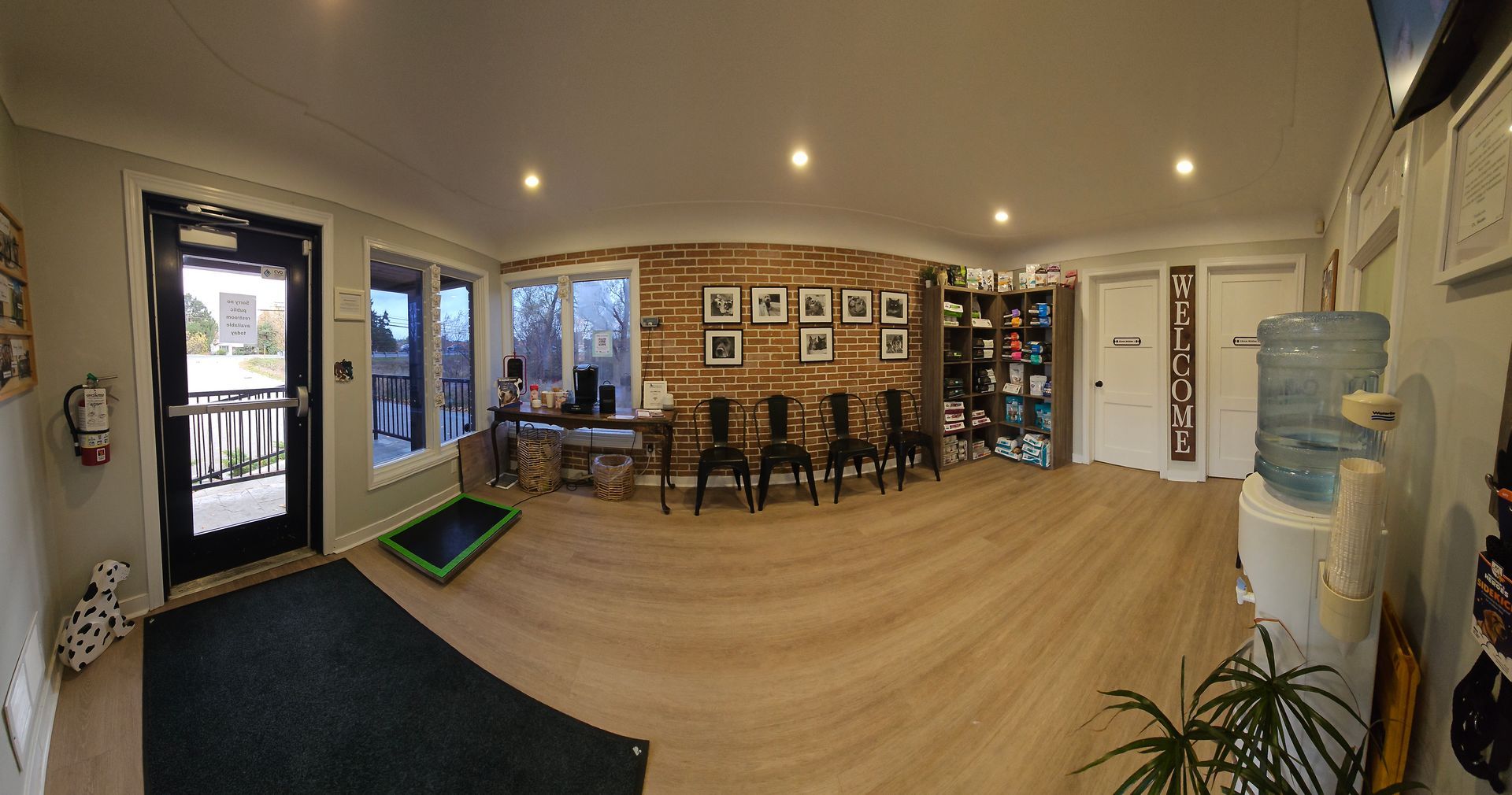 Reception area with light wood floors, a brick wall, and a water cooler. Entrance on the left.
