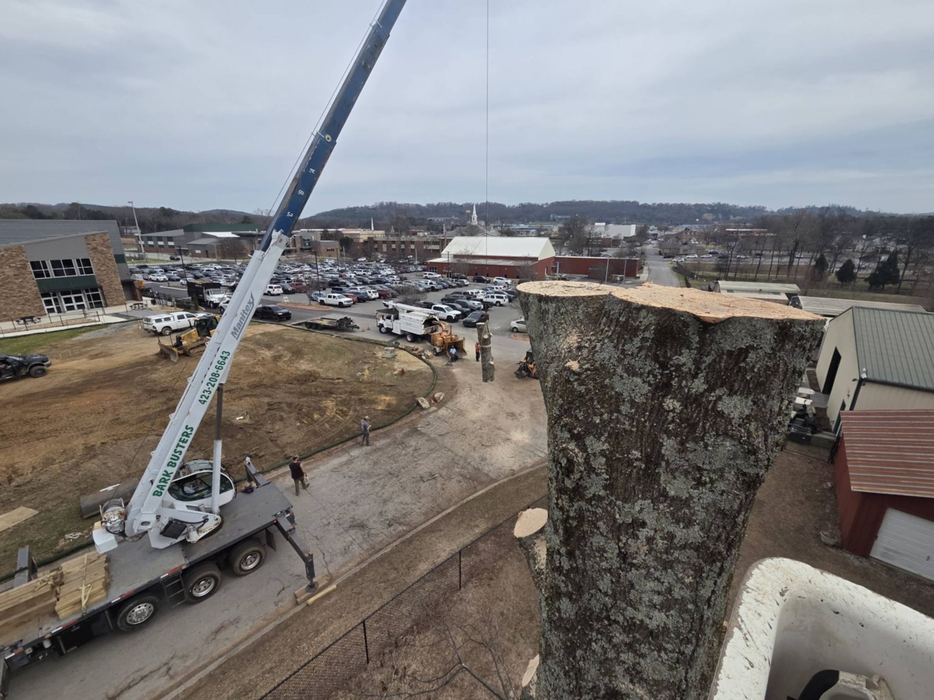 Construction site viewed from a rooftop, with a large crane and scattered equipment under a cloudy sky
