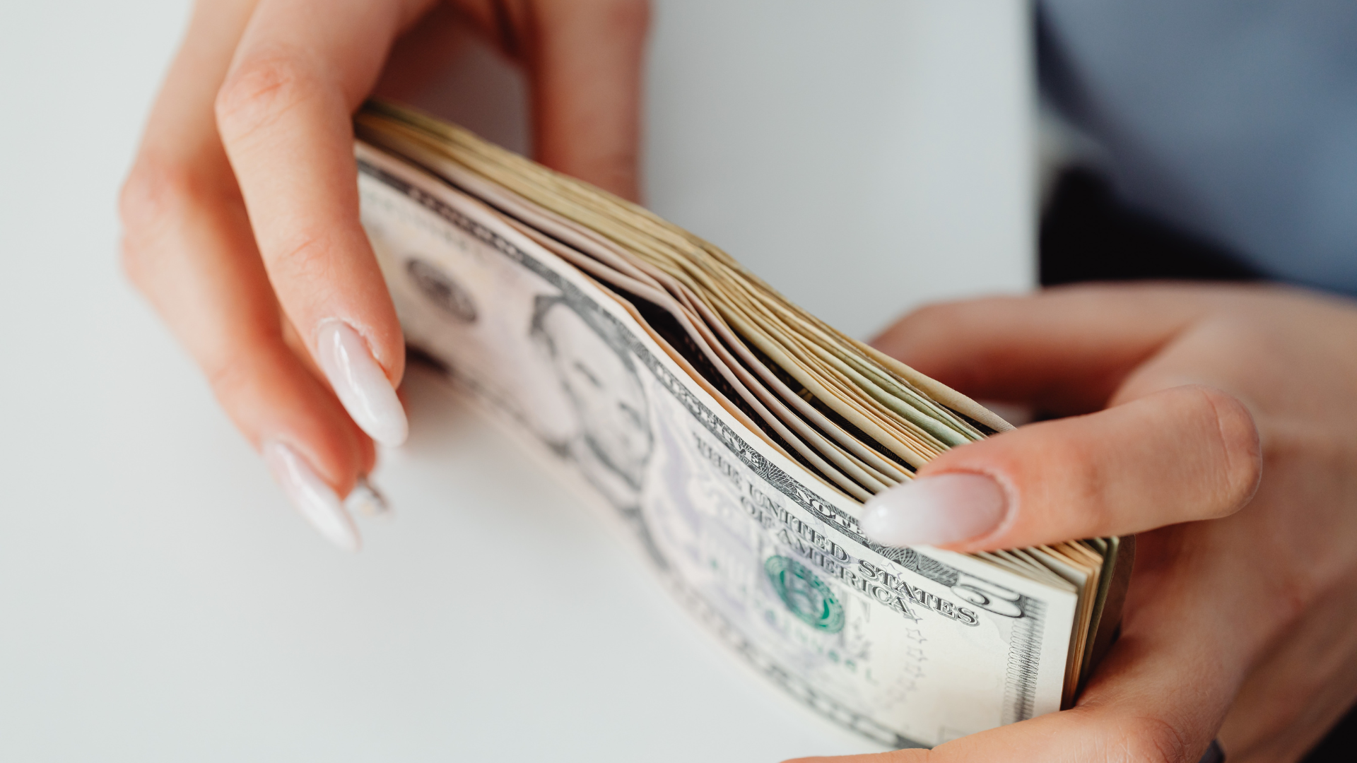 person holding a stack of cash as savings