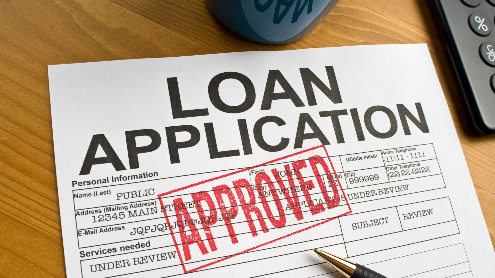 Loan application form with a red “APPROVED” stamp on a desk