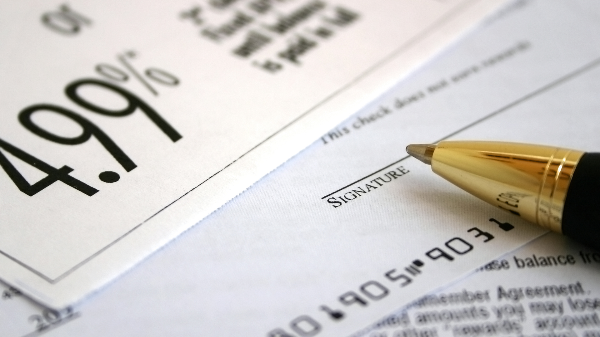 4.99% interest rate on a document with a gold pen pointing at a signature line
