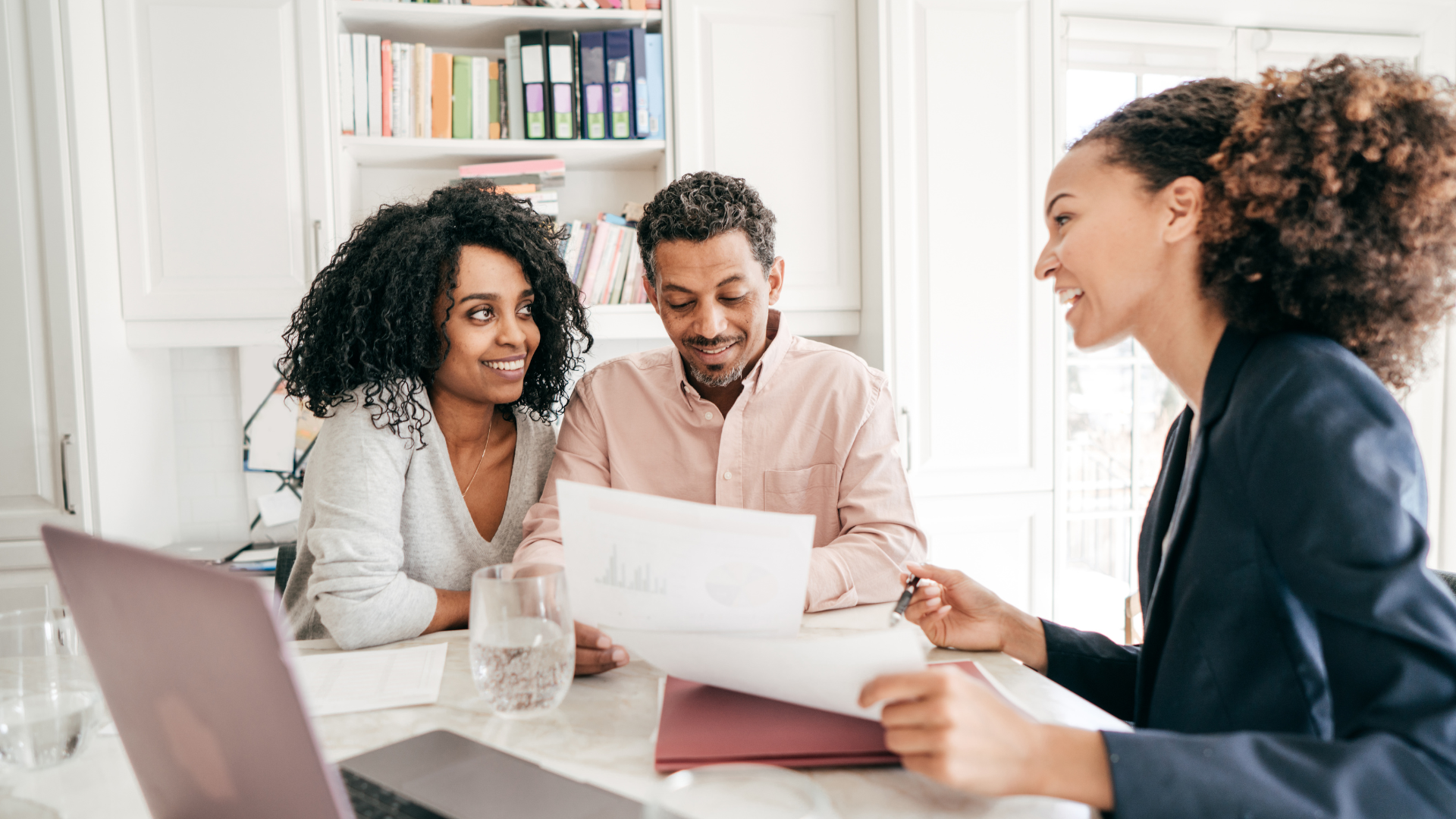 Three coworkers reviewing loan agreement documents in a bright office meeting room