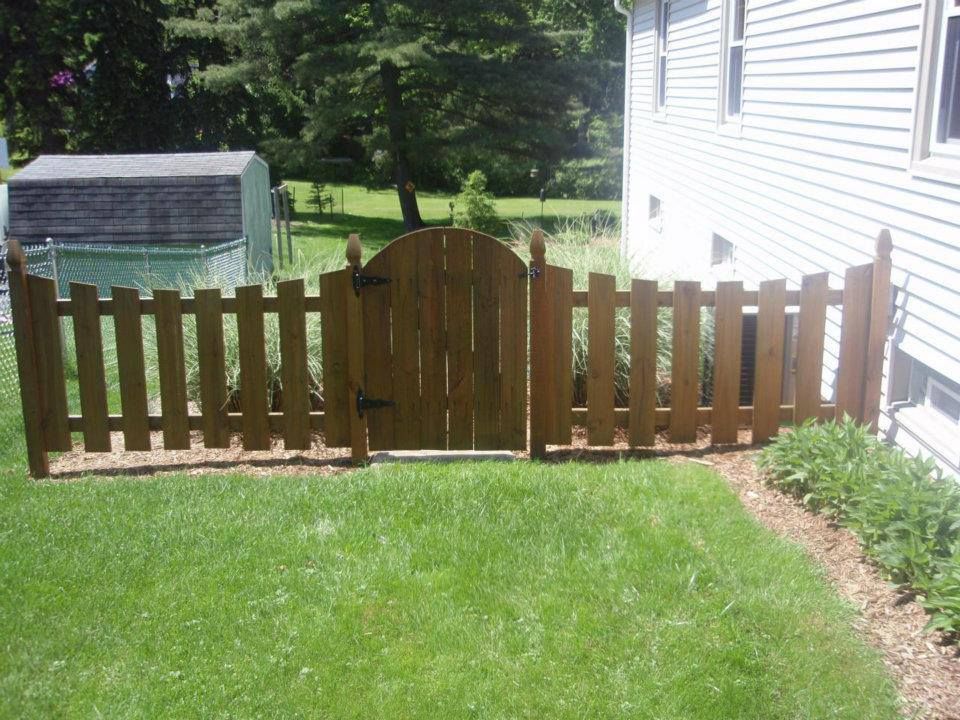 A wooden picket fence with a gate in front of a house