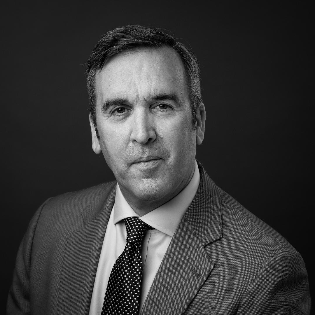 Man in suit and tie, looking directly at the viewer. Black and white, formal portrait.