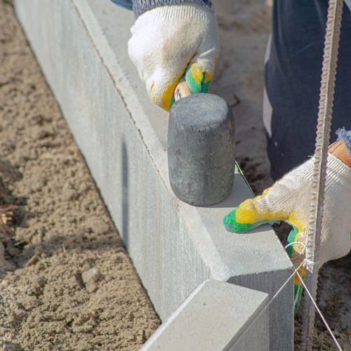 A person is using a hammer to hammer a concrete block.