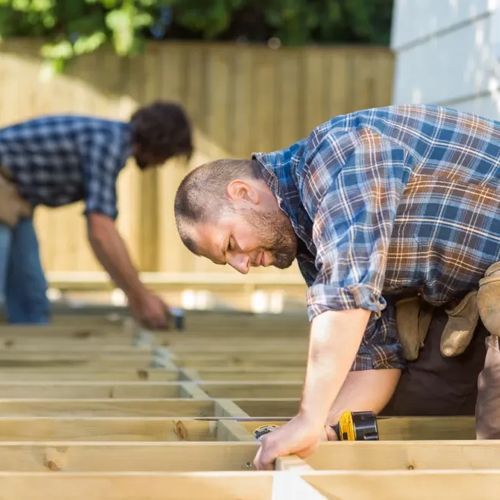 Two men are working on a wooden deck.