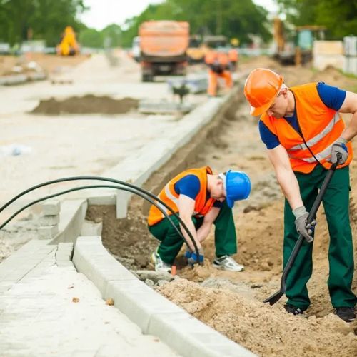 Two construction workers are working on a road