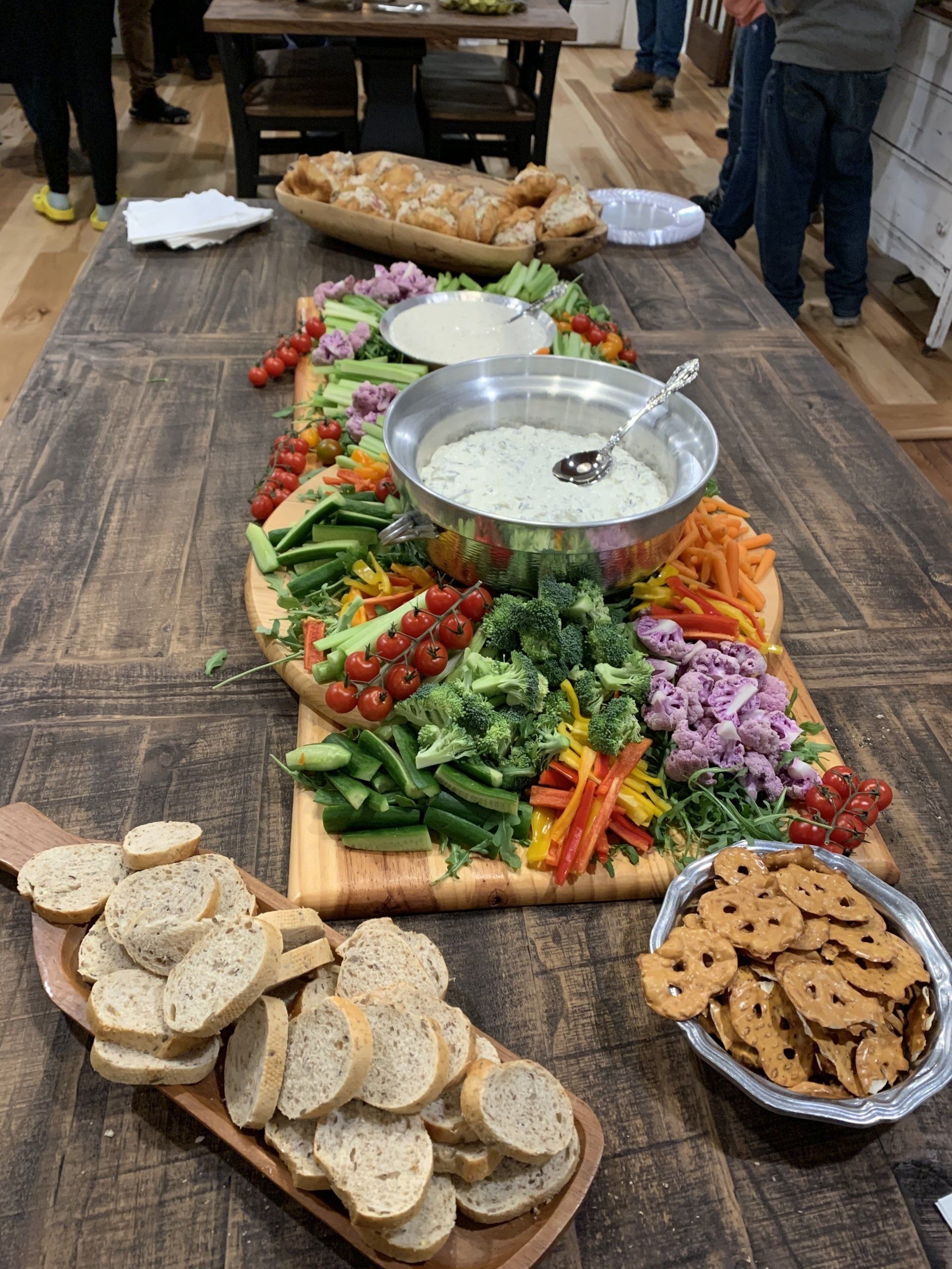 A wooden table topped with a variety of vegetables and crackers.