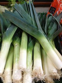 A bunch of leeks are sitting on top of each other on a table.