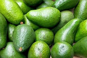 A pile of green avocados sitting on top of each other on a table.