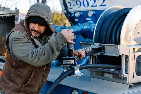 A man in a hooded jacket is working on a machine.