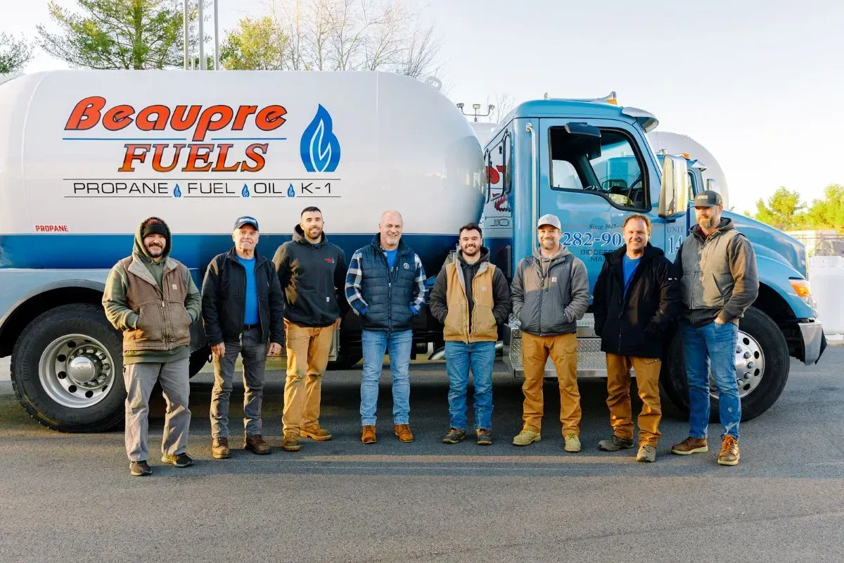 A group of men are standing in front of a beaupre fuels truck.