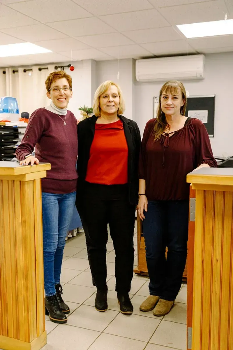 Three women are standing next to each other in a room.