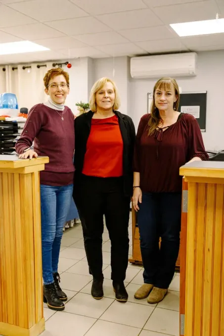 Three women are standing next to each other in a room.