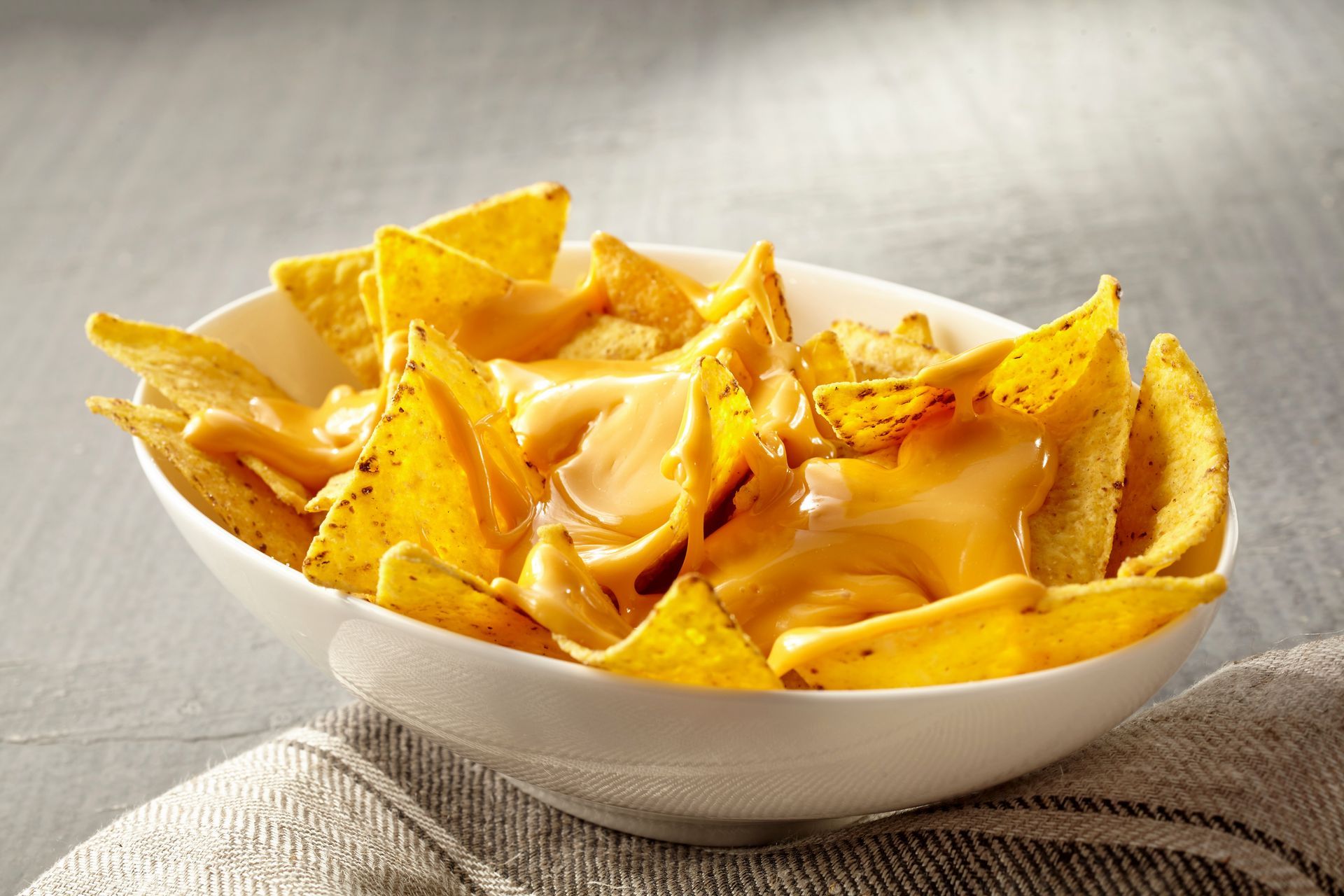 Bowl of tortilla chips covered in melted cheese.