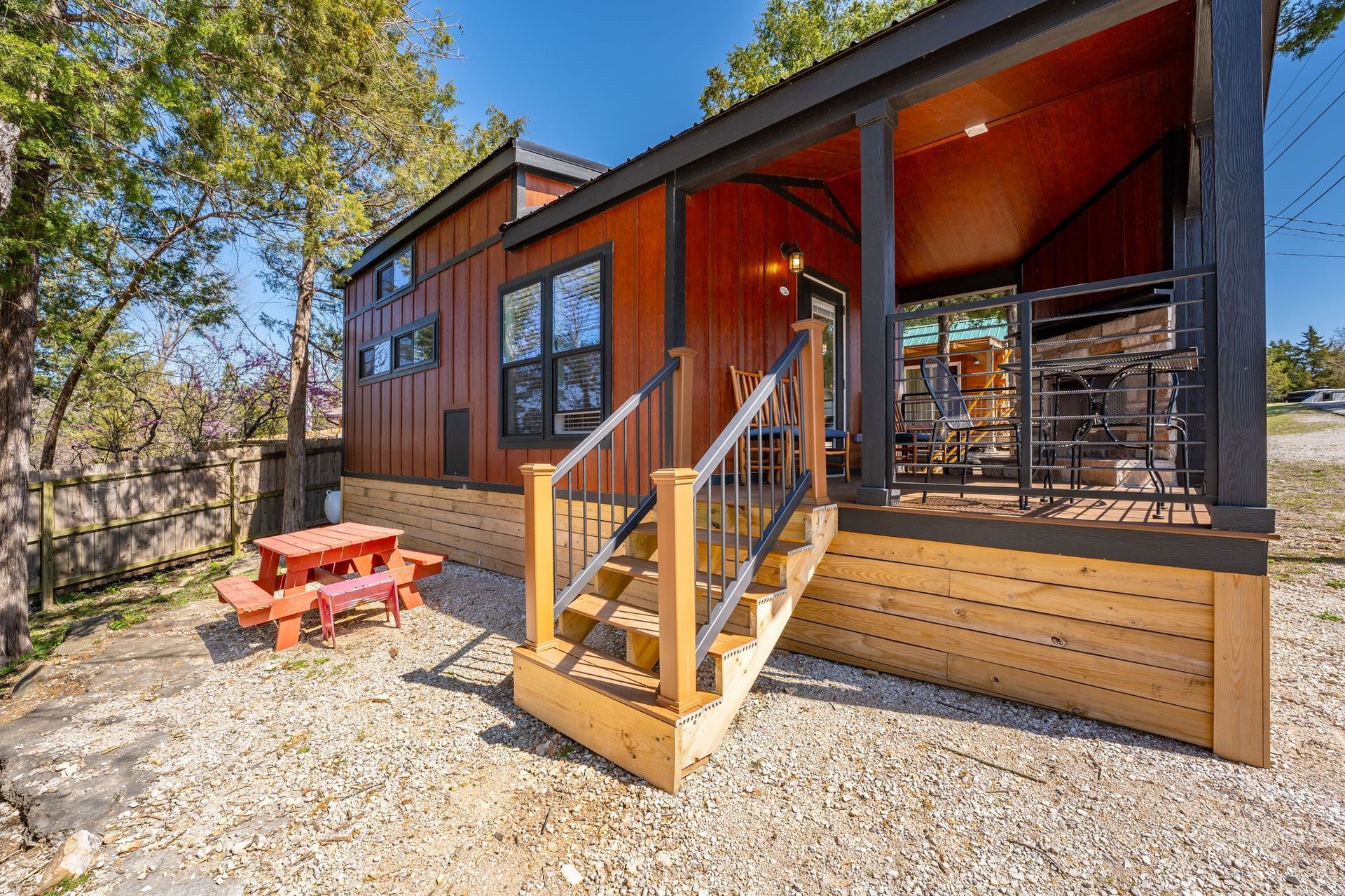 Cabin exterior with porch, stairs, picnic table, and gravel ground.