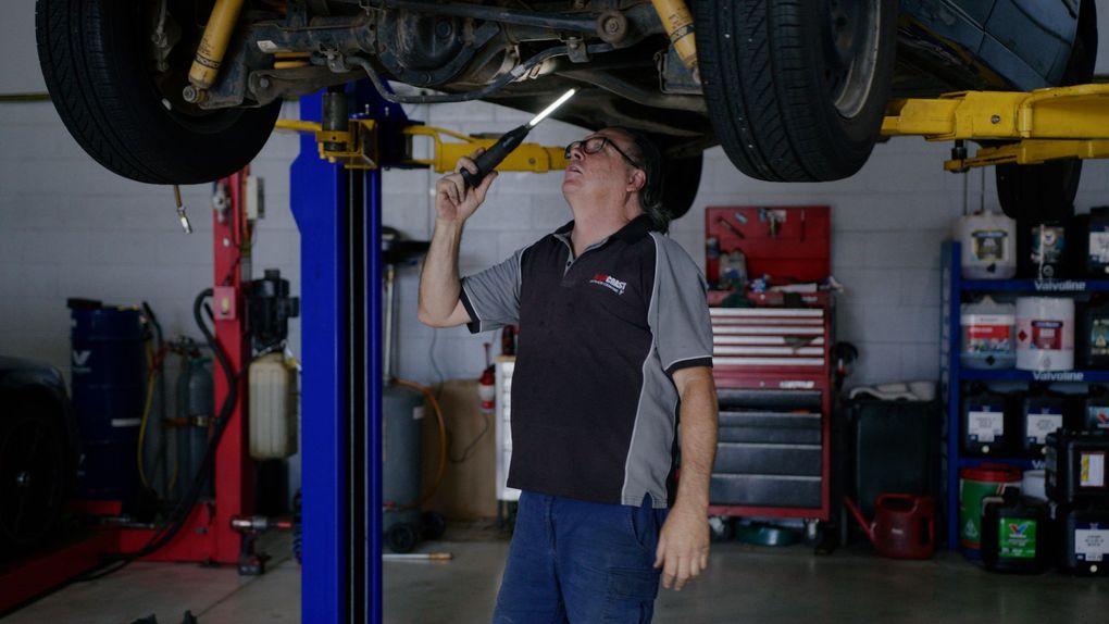 Mechanic inspecting a car on a lift in an auto repair shop