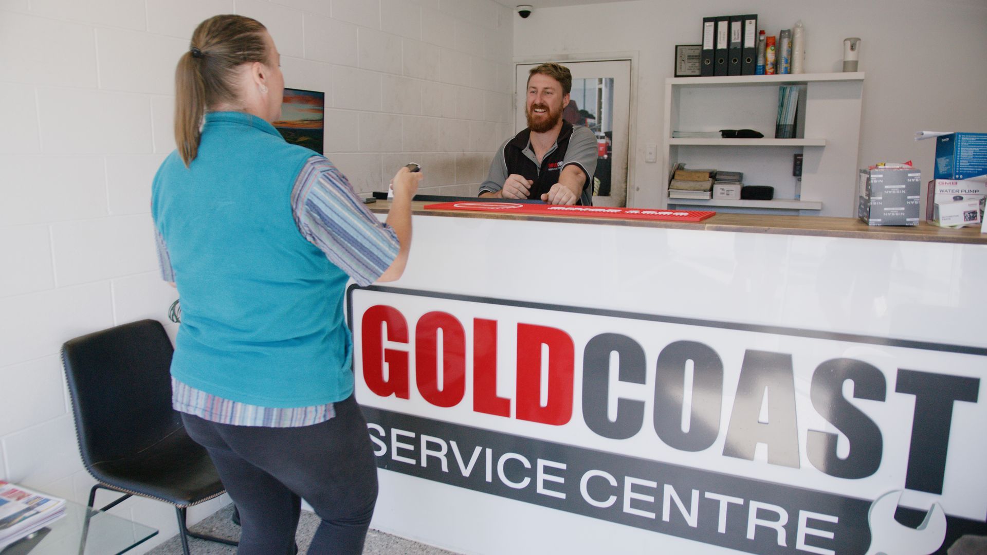 Customer at Gold Coast Service Centre counter speaking with staff in a bright office.