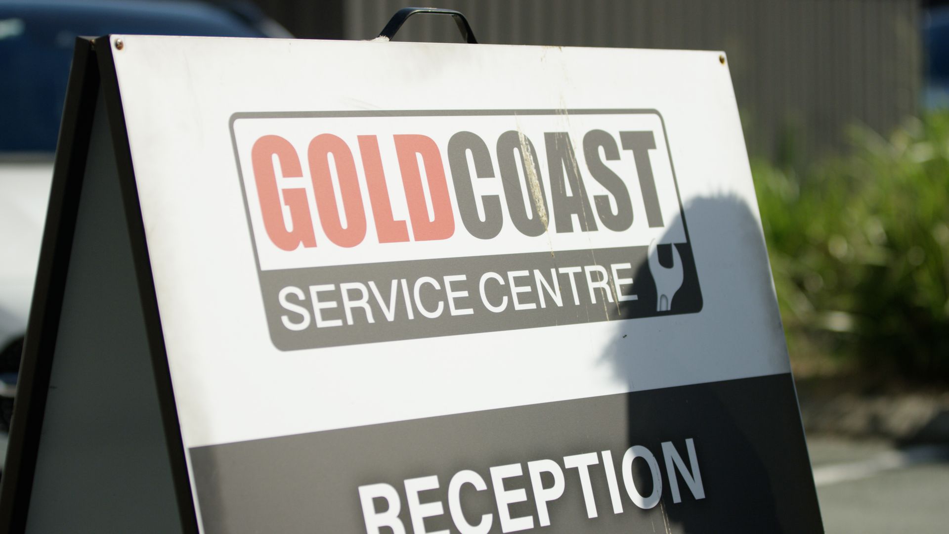 Gold Coast Service Centre reception sign on a white board outdoors