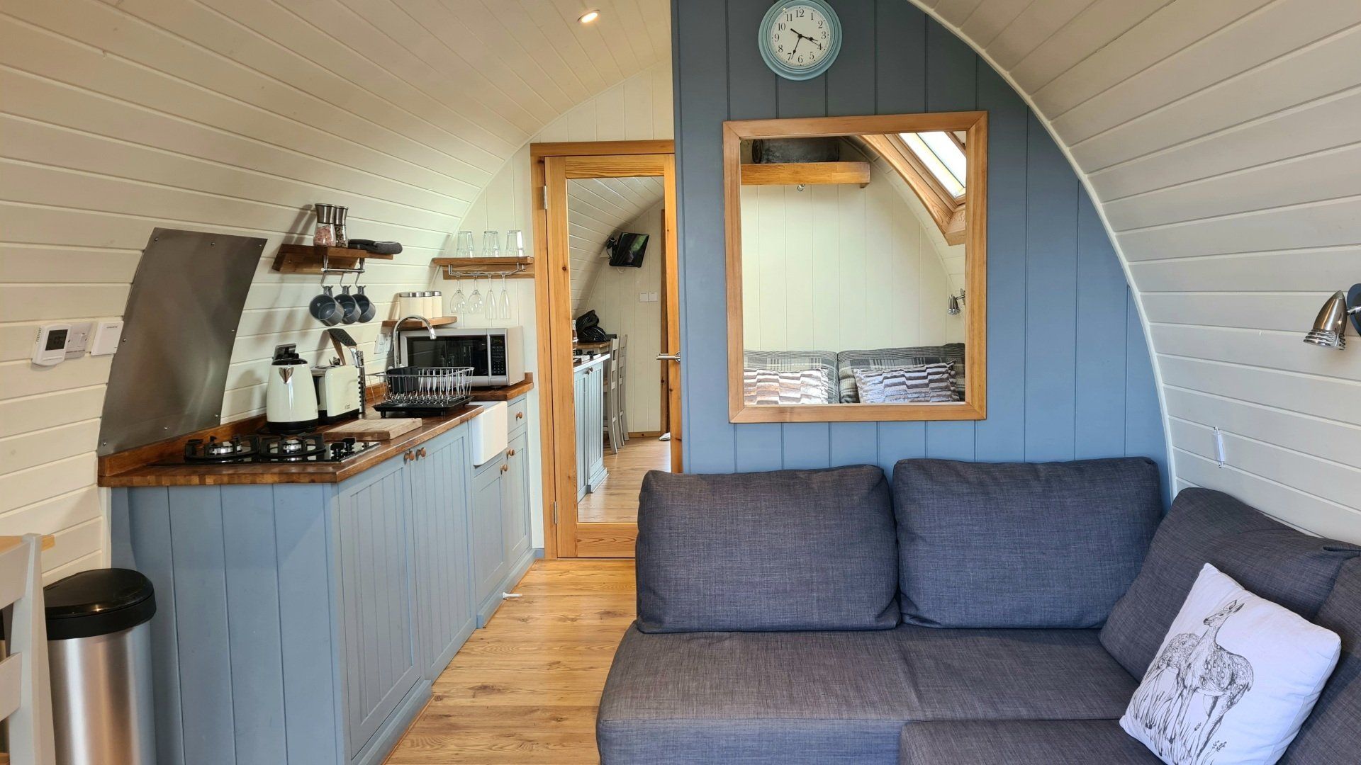 A living room with a couch and a kitchen in a pod.