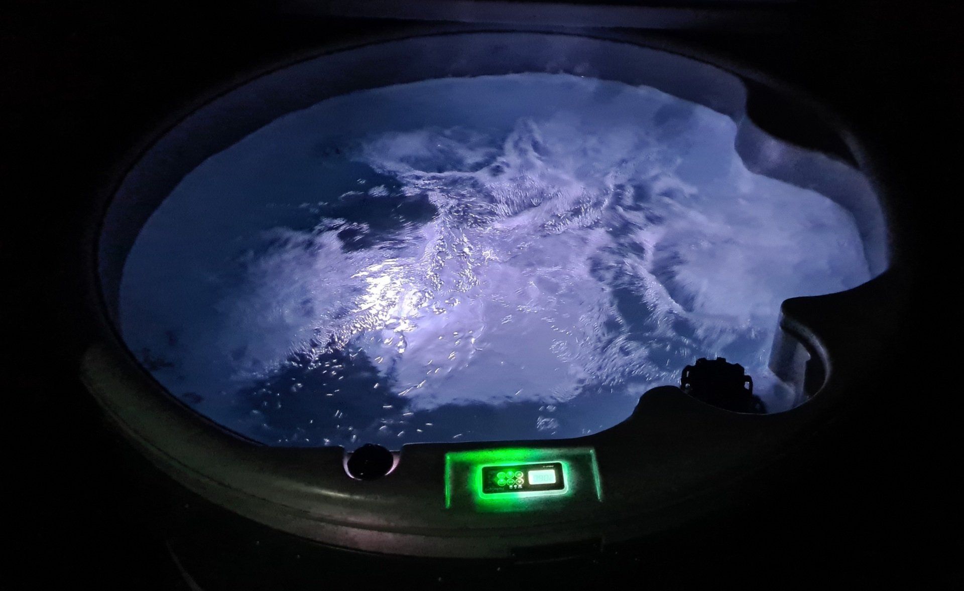 A person is sitting in a hot tub at night.