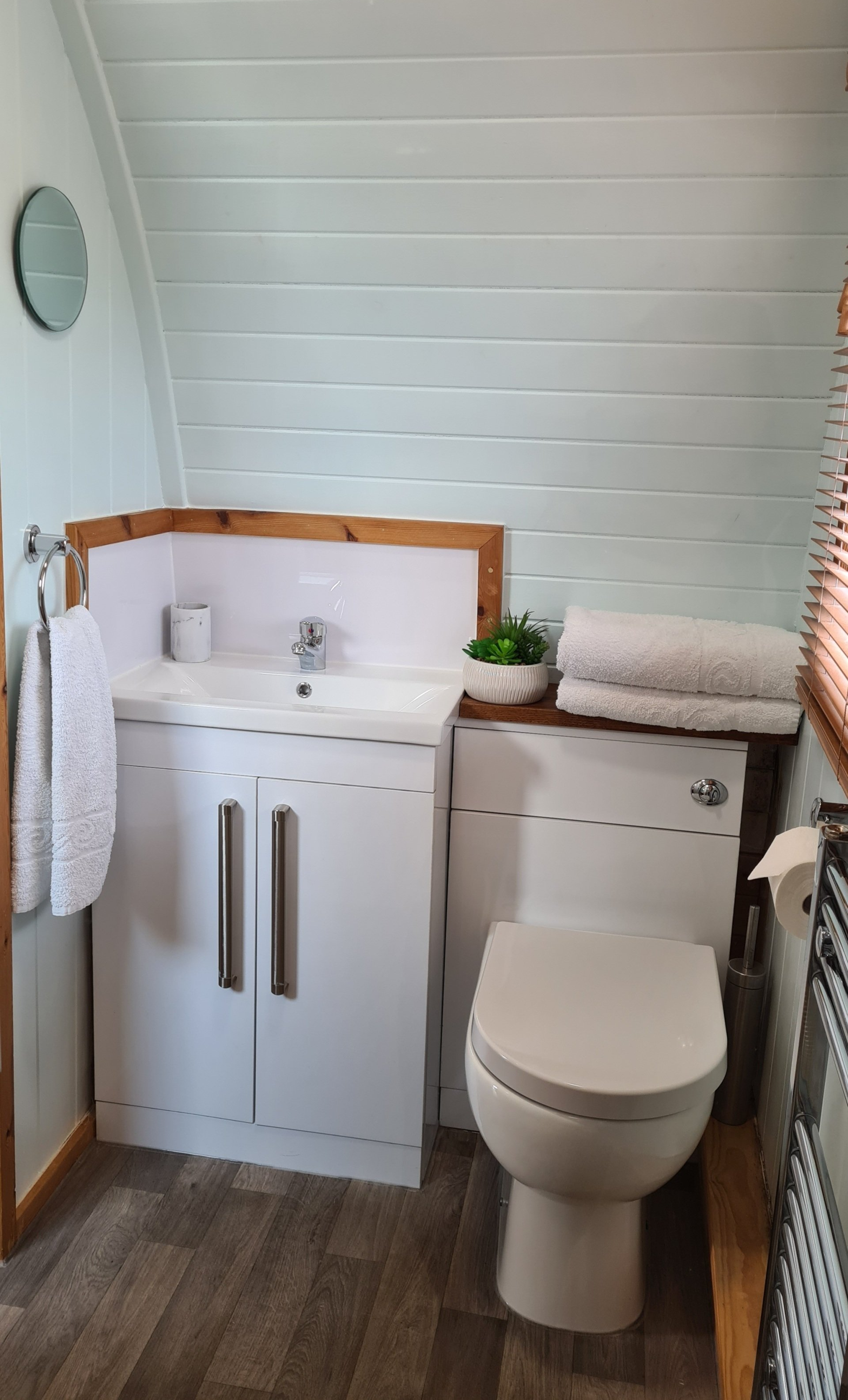 A bathroom with a toilet , sink and mirror.