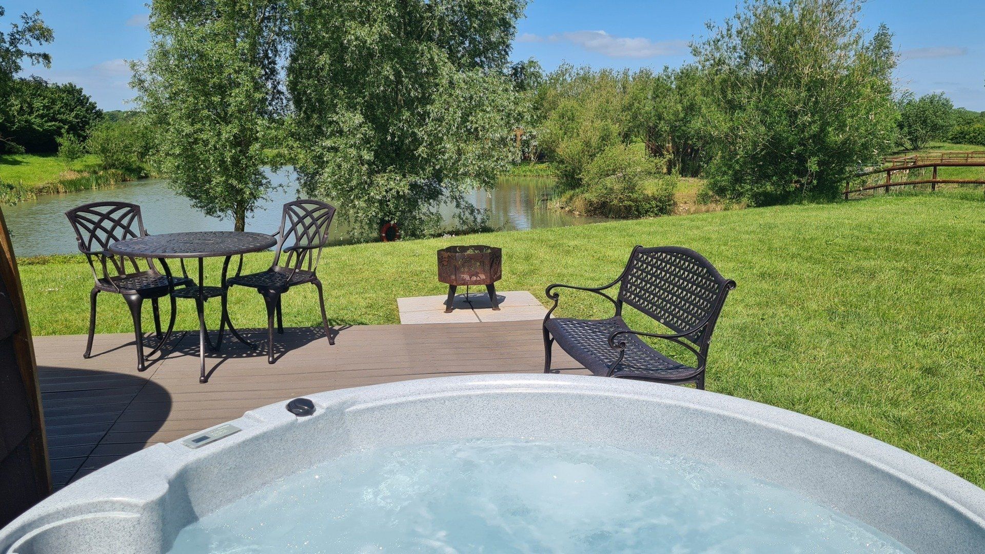 A hot tub is sitting on a deck next to a table and chairs.
