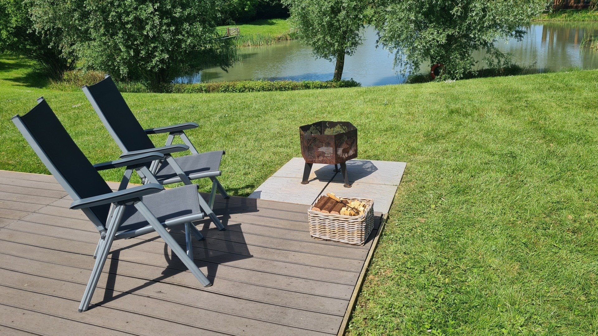 Two chairs are sitting on a deck next to a fire pit.