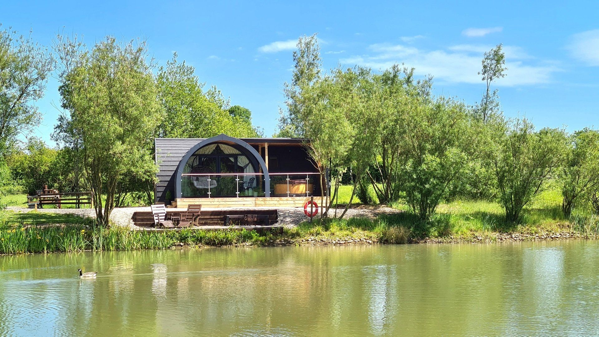 A small house is sitting on the shore of a lake surrounded by trees.
