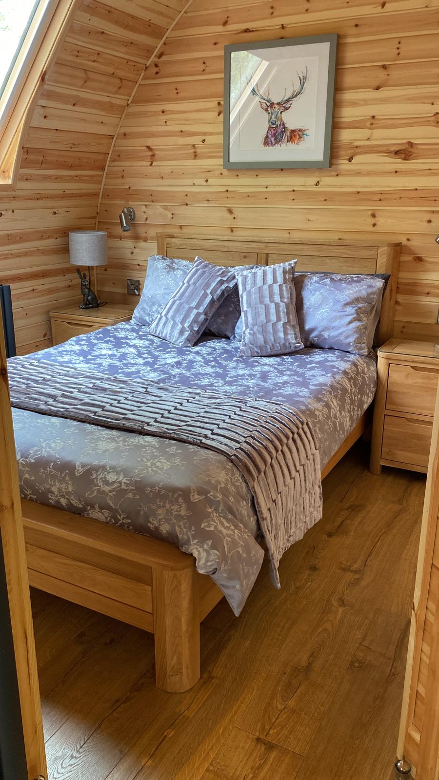 A bedroom with a bed , nightstands , and a picture on the wall.