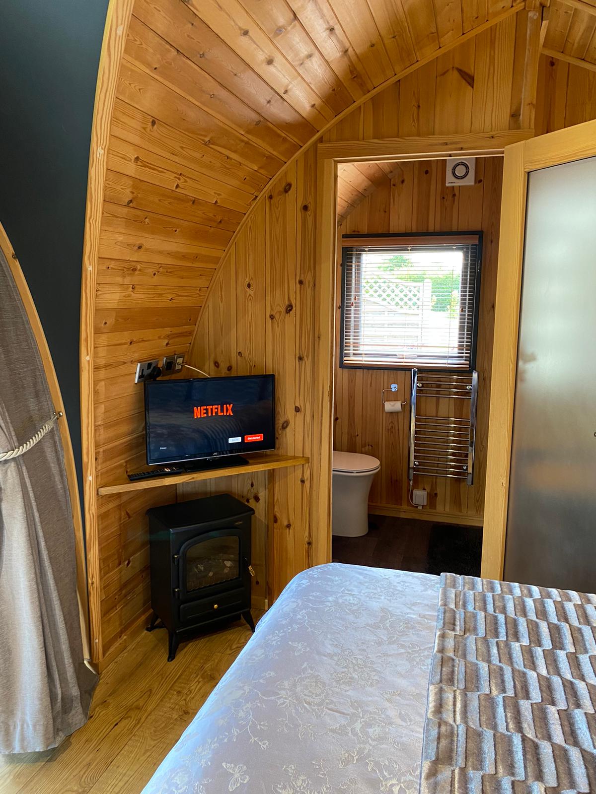 A bedroom with a bed , television , stove and toilet.