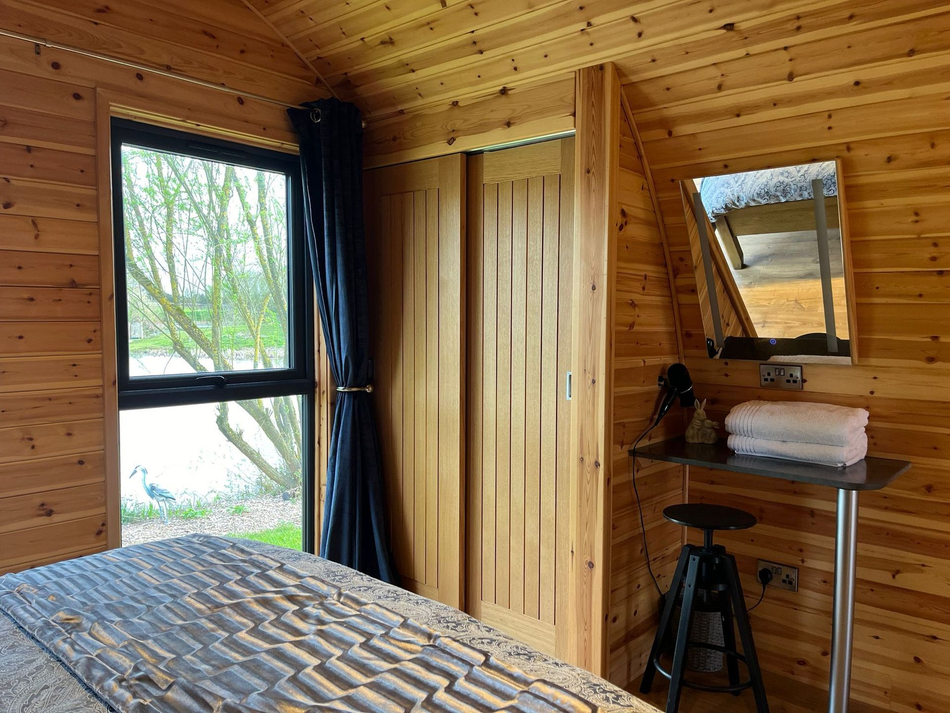 A bedroom with a bed , dresser , mirror and window.
