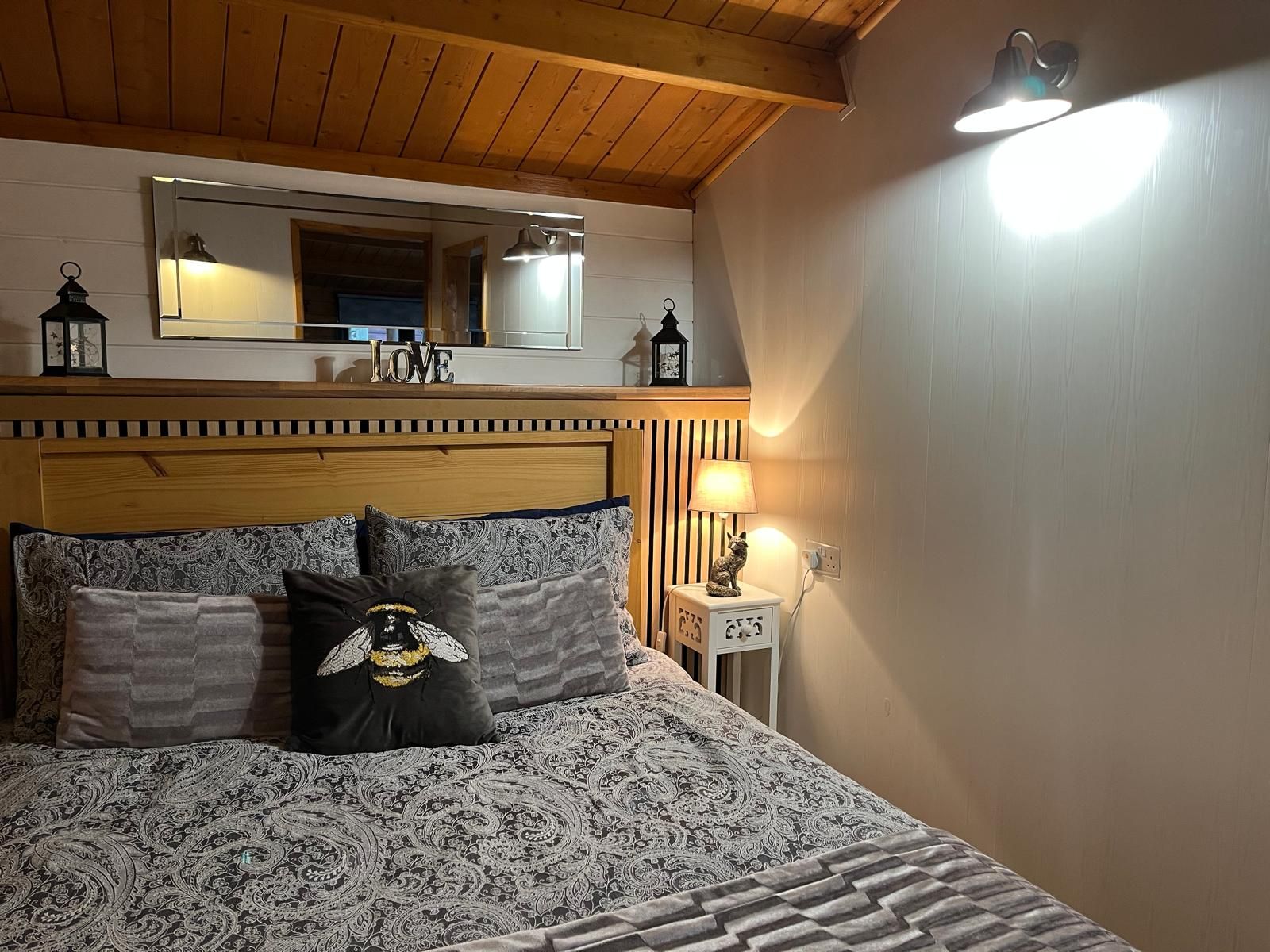 A bedroom with a bed , nightstand , and mirror.