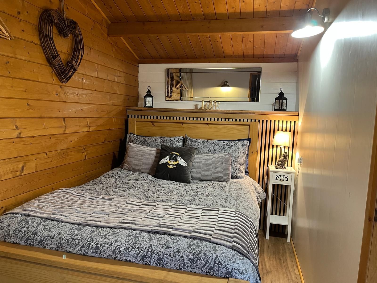 A bedroom with a bed , nightstand , and mirror.